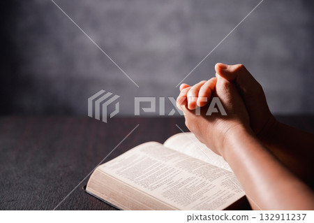 Bible in hand, christian lifts prayer in worship, holding firmly to holy concept of faith, hope and deep belief guides their spiritual life. Hands together in prayer to God along with bible Bible in hand, christian lifts prayer in worship, holding firmly to holy concept of faith, hope and deep belief guides their spiritual life. Hands together in prayer to God along with bible 132911237