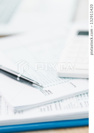 Concept of tax filing and accounting. Close up of US individual income tax return form with pen and calculator on office desk, symbolizing financial planning, budget management and payment accuracy. 132911420