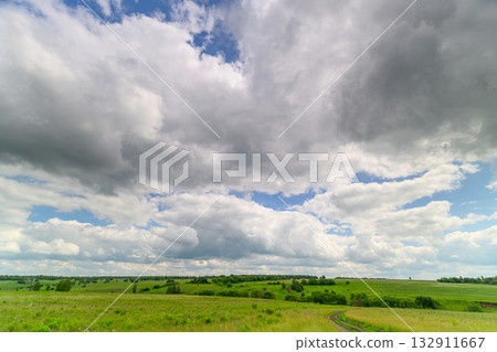 A Vast, Expansive Green Landscape Set Against a Dramatic and Cloudy Sky Above It A Vast, Expansive Green Landscape Set Against a Dramatic and Cloudy Sky Above It 132911667