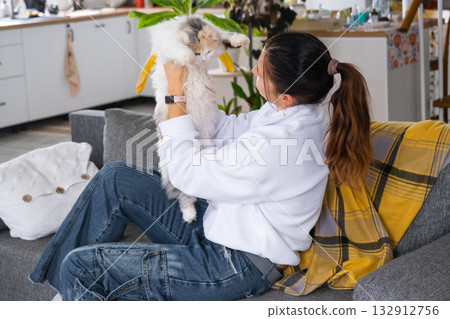 A woman takes care of a domestic cat, combs its fur with a comb 132912756