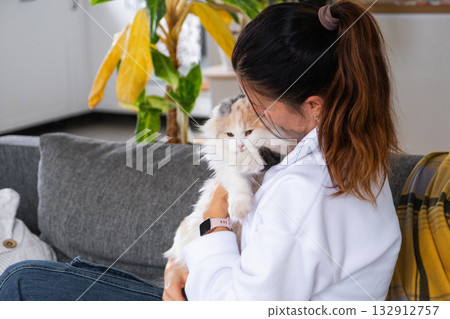 A woman takes care of a domestic cat, combs its fur with a comb A woman takes care of a domestic cat, combs its fur with a comb 132912757