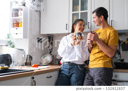 Husband and wife drinking coffee together in the morning in the kitchen Husband and wife drinking coffee together in the morning in the kitchen 132912837
