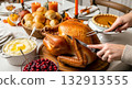 Hands carving a roasted turkey on a festive dining table with pumpkin pie and mashed potatoes for a holiday dinner. 132913555
