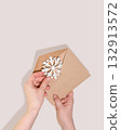 Hands Holding Kraft Envelope With Paper Snowflake For Winter Holiday Greeting Cards, Christmas Gift Packaging, DIY Crafts, Seasonal Invitations, And Minimalist Festive Stationery Concepts 132913572