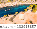 Tourists explore a historic tower and a luxury yacht anchors in a Majorca cove 132913857