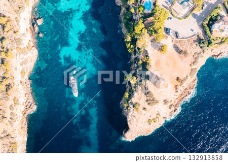 Yacht anchored in turquoise waters near a cliffside villa and historic tower in Majorca Yacht anchored in turquoise waters near a cliffside villa and historic tower in Majorca 132913858