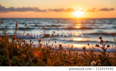 A serene coastal sunset scene, with the warm glow of the sun setting behind the horizon line 132914540
