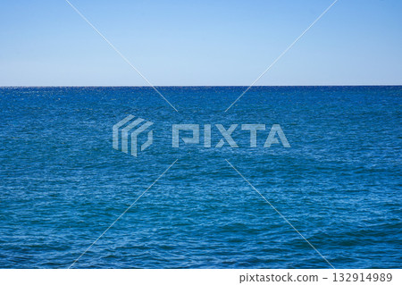 Expansive Azure Ocean Under a Clear Sky, Showcasing Tranquil Waters and Endless Horizon as Daylight Illuminates the Serene Coastal View 132914989