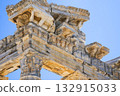 Intricate Architectural Details of Ancient Columns Showcasing Sculpted Figures Against a Clear Blue Sky 132915033