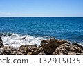 A Tranquil Coastal Scene with Lapping Waves Against Rocky Shoreline Under Clear Blue Skies Reflecting the Beauty of Nature's Harmony 132915035