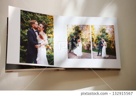 an open photo book with wedding photos on a white table an open photo book with wedding photos on a white table 132915567