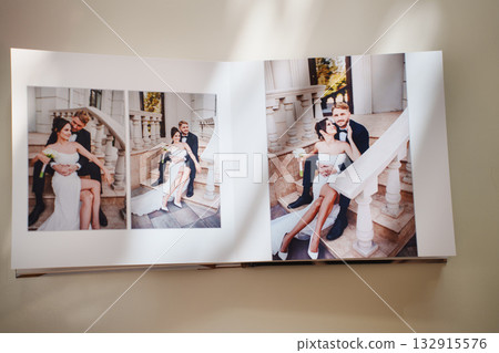 an open photo book with wedding photos on a white table 132915576