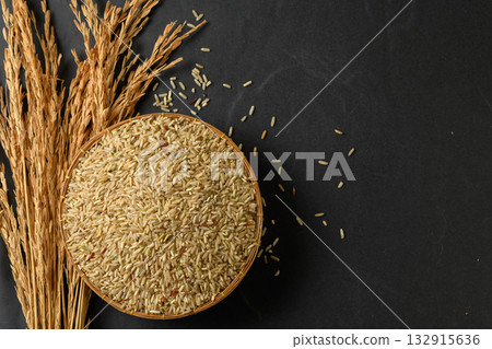 Top view of a round, traditional woven basket filled with uncooked brown rice grains. Top view of a round, traditional woven basket filled with uncooked brown rice grains. 132915636