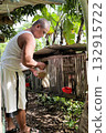 A Filipino man feeds chickens in a bamboo cage on his private mini farm 132915722