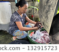 An Asian woman washes clothes by hand in a basin 132915723
