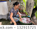 An Asian woman washes clothes by hand in a basin 132915725