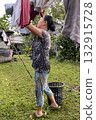 An Asian woman hangs laundry on a line in the yard 132915728