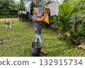 An Asian woman hangs laundry on a line in the yard 132915734