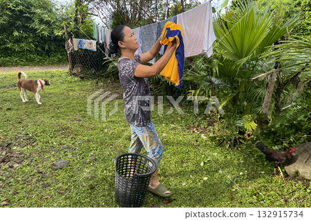 An Asian woman hangs laundry on a line in the yard 132915734