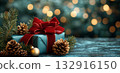 Christmas gift box with a velvet red bow, surrounded by fir branches, cones, and bokeh lights on a dark background. 132916150