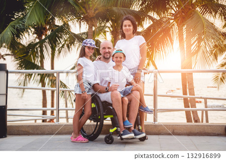 Disabled man in a wheelchair with his family on the beach. 132916899