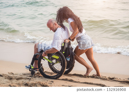 Disabled man in a wheelchair with his wife on the beach. 132916908