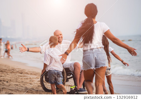 Disabled man in a wheelchair with his family on the beach. Disabled man in a wheelchair with his family on the beach. 132916912