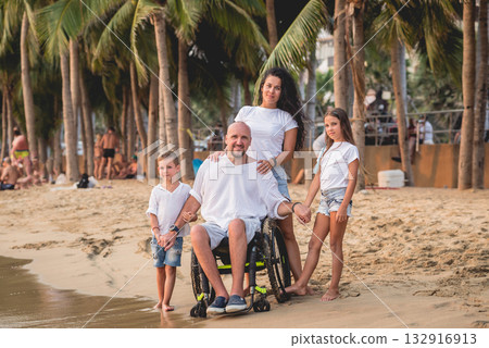 Disabled man in a wheelchair with his family on the beach. Disabled man in a wheelchair with his family on the beach. 132916913