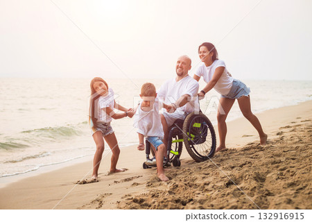 Disabled man in a wheelchair with his family on the beach. 132916915