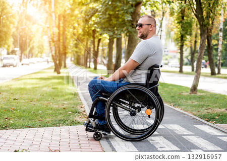 Handicapped man in wheelchair preparing to cross the road on pedestrian crossing Handicapped man in wheelchair preparing to cross the road on pedestrian crossing 132916957
