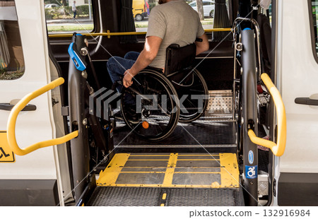 A man in a wheelchair on a lift of a vehicle for people with disabilities A man in a wheelchair on a lift of a vehicle for people with disabilities 132916984