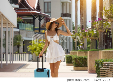 A woman in a white dress with a blue suitcase walking in boat marina A woman in a white dress with a blue suitcase walking in boat marina 132917203
