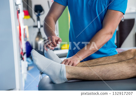 Rehabilitation therapy. Physiotherapist working with young male patient Rehabilitation therapy. Physiotherapist working with young male patient 132917207