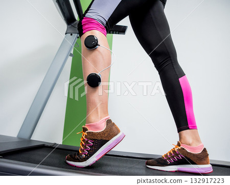 Young sports woman with electrostimulator on the muscles of the legs. Young sports woman with electrostimulator on the muscles of the legs. 132917223