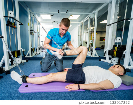 Rehabilitation therapy. Young man doing exercises on mat Rehabilitation therapy. Young man doing exercises on mat 132917232
