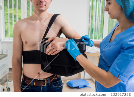 Nurse putting a sling on patients arm that is broken. Injury 132917238