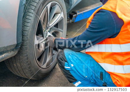 Mechanic using an impact wrench to remove lug nuts from a car wheel. Seasonal tire change and professional car service in preparation for winter. Mechanic using an impact wrench to remove lug nuts from a car wheel. Seasonal tire change and professional car service in preparation for winter. 132917503