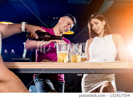 Cheerful friends in the pub. Drinking beer, talking, having fun. 132917504