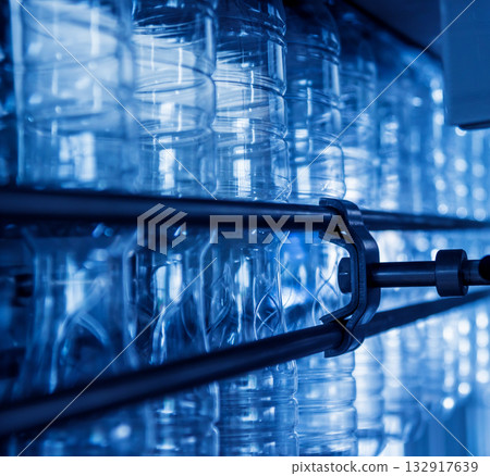 Automatic filling machine pours water into plastic PET bottles. 132917639