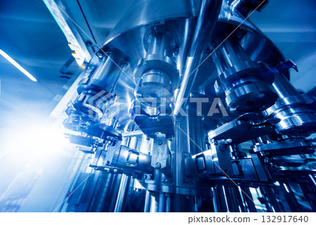 Automatic filling machine pours water into plastic PET bottles. 132917640