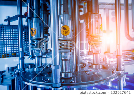 Automatic filling machine pours water into plastic PET bottles. 132917641