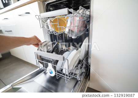 girl cleaning the kitchen putting dishes in the dishwasher for cleanliness girl cleaning the kitchen putting dishes in the dishwasher for cleanliness 132919087