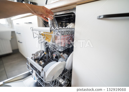 girl cleaning the kitchen putting dishes in the dishwasher for cleanliness girl cleaning the kitchen putting dishes in the dishwasher for cleanliness 132919088