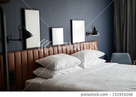 modern designer hotel room interior with a large bed and lamps with paintings on the wall 132919206