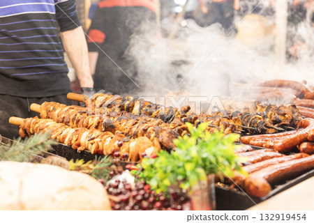 vendor fries meat and sausage on the grill in the city center at the Christmas market in Krakow Poland vendor fries meat and sausage on the grill in the city center at the Christmas market in Krakow Poland 132919454
