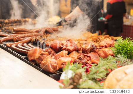 vendor fries meat and sausage on the grill in the city center at the Christmas market in Krakow Poland vendor fries meat and sausage on the grill in the city center at the Christmas market in Krakow Poland 132919483