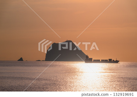 Cargo Ship Sailing Past Keelung Islet at Sunrise in Waishuangxi Keelung Taiwan. Cargo Ship Sailing Past Keelung Islet at Sunrise in Waishuangxi Keelung Taiwan. 132919691