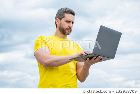 busy man working online on laptop on sky background busy man working online on laptop on sky background 132919709