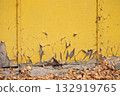 a worn part of a yellow wall against a background of autumn leaves 132919765