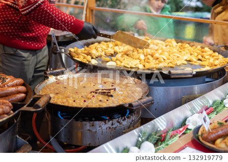 vendor fries meat and sausage on the grill in the city center at the Christmas market in Tallinn Estonia vendor fries meat and sausage on the grill in the city center at the Christmas market in Tallinn Estonia 132919779